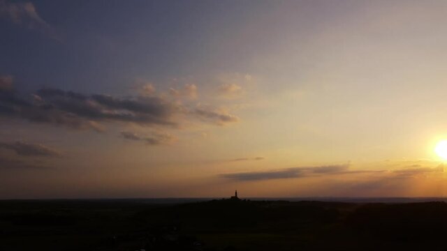Drone panning over Bavarian rural landscape with Eichlberg pilgrimage church atop of a hill in evening sunlight