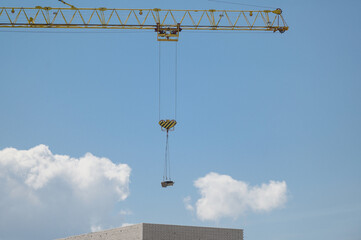 Obraz premium A tower crane lifts a load against the sky. Boom of a construction crane