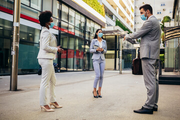 Three employers standing in social distance wearing face mask looking at each other and talking