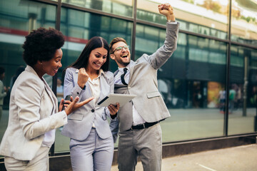 Business team celebrating a triumph, looking at digital tablet.