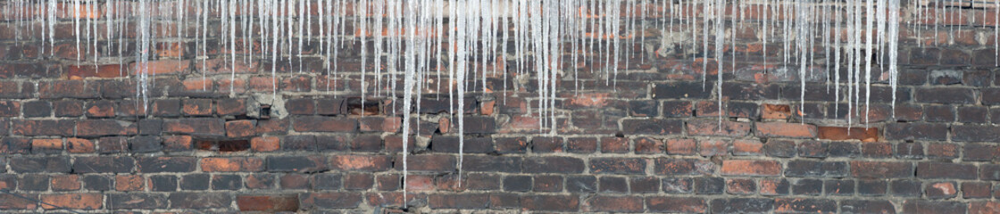 large group of icicles on dark bricks background