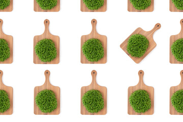 Microgreen alfalfa sprouts on a wooden cutting board pattern on a white concrete background.