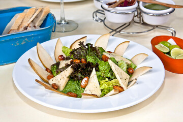 Sliced pear salad with cheese and caramelized almonds, fresh green salad on restaurant table