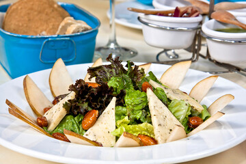 Sliced pear salad with cheese and caramelized almonds, fresh green salad on restaurant table