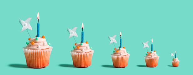 Big and small celebratory cupcakes with decorative lit candles