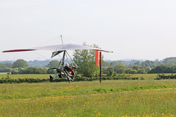 Fototapeta premium Ultralight airplane landing on a farm strip 