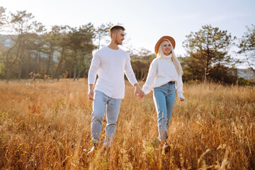 Young couple having fun walking and hugging during autumn sunny day. Enjoying time together. The concept of youth, love and lifestyle.