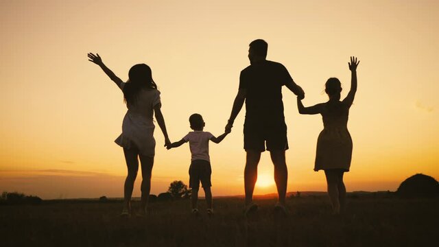 Happy family, parents and childrens silhouettes playing on park. Silhouette family at sunset. Teamwork child and parents run fun in the park. Friendly family and teamwork kid dream concept.