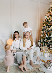 Happy cheerful family with children celebrate the Christmas holiday give gift boxes have fun decorate the Christmas tree in the festive interior of the house, selective focus