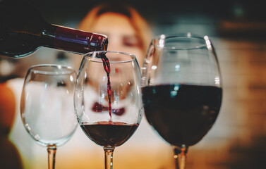 bartender pouring red wine into a glass in cafe or bar