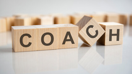 word COACH on wooden cubes, gray background