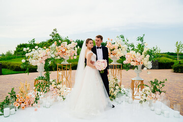 bride and groom in the wedding ceremony area of live white and pink flowers. 