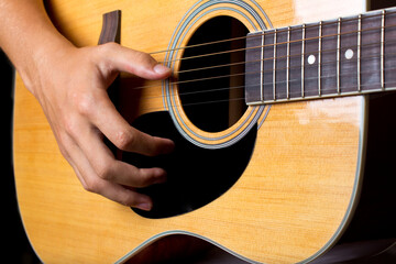 Acoustic guitar and man's hand strumming guitar chords close up photo