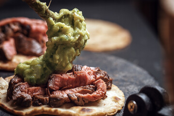 Process of cooking tacos with grilled flank beef steak with handmade guacamole on tortilla iron press
