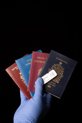 hand with glove holding passports and covid test over dark background