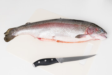 red fish and knife lie on a white cutting board