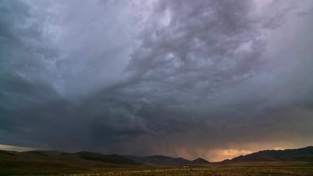 Lightning flashing as storm clouds move over the landscape in Utah during sunset.