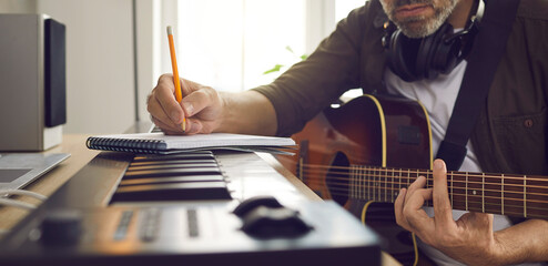 Musician writing music. Songwriter who's following his passion sitting by electronic keyboard in...