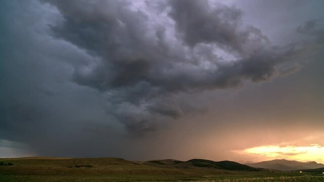 Flashing lighting strikes during extreme thunderstorm timelapse at sunset moving over the landscape in Utah.