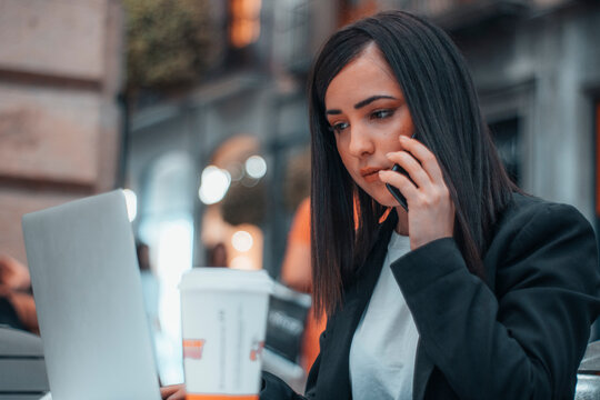 Asesora realizando una llamada telef&oacute;nica con su telefono m&oacute;vil a un cliente para comentar diversos asuntos sobre su trabajo en una cafeteria por la ma&ntilde;ana tomando caf&eacute; y mirando el port&aacute;til