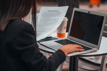 Abogada con seriedad escribiendo ideas y planteamientos en su ordenador laptop en una cafeteria de su ciudad tomando café por la mañana para terminar su trabajo