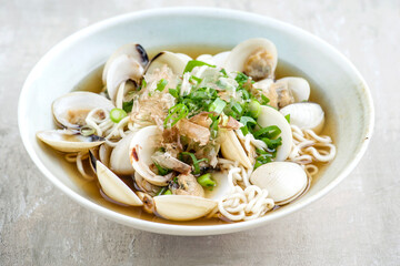 Traditional Japanese mussel ramen soup with noodles and bonito flakes served as close-up in a design bowl
