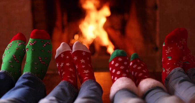 Happy family wearing Christmas socks relaxing near fireplace