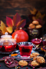 Glass cup of hot red tea and fresh homemade delicious apple cookies on rustic autumn background