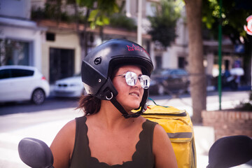 Fototapeta na wymiar Chica latina repartiendo con moto para empresas de delivery de comida rápida y de restaurantes