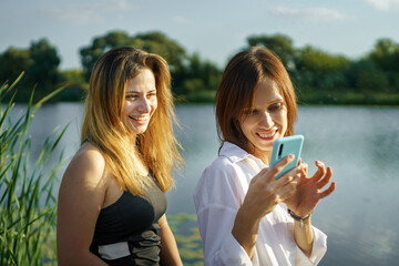 Happy millennial women friend enjoying activities in nature take selfie by smartphone