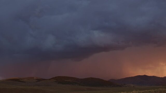 Lightning bolts flashing through the sky at sunset panning over the horizon in Utah.