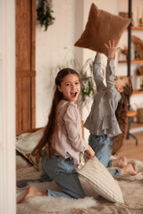 Two girls playing throwing pillows on the bed on christmas morning