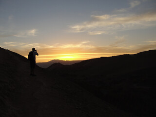 Fototapeta na wymiar Man taking pictures of the sunset in Valle de la Luna, Atacama Desert, Chile.