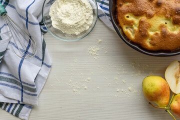 Homemade pear pie on a white table with pears in the background. Copy space.