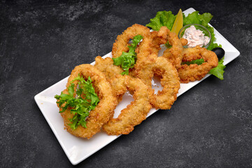 Squid rings fried in batter on a dark background soft focus