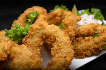 Squid rings fried in batter on a dark background soft focus