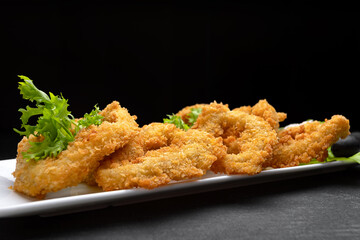 Squid rings fried in batter on a dark background soft focus