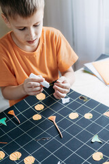 Child creating Halloween themed board game sittinf by desk