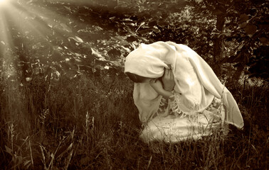 Praying woman on grass lawn