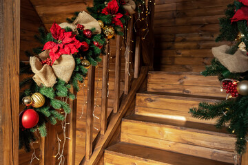 Detail house wooden staricase handrails railings decorated with artificial holly poinsettia flower,...