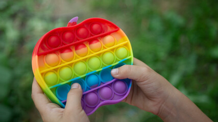 Rainbow colorful anti stress pop it in kid girl hands. Fidget popular trendy children toy for playing and develop motor skills. Copy space. Simple dimple. 