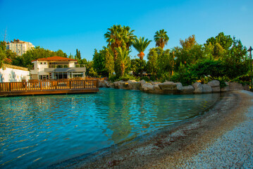 Obraz premium ANTALYA, TURKEY: Landscape with a view of a beautiful park with a fountain and a pond in Antalya on a sunny summer day.