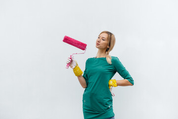 A young girl poses with a pink roller before painting a white wall. Repair of the interior.