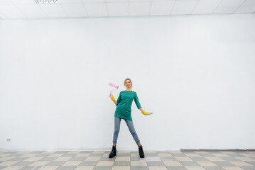 A young girl poses with a roller in front of a white wall. Repair of the interior.