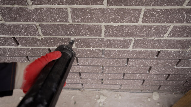 Repair in apartments and houses concept. The master sews seams on the brickwork. Joints in brickwork. Grouting with tiling fugue.