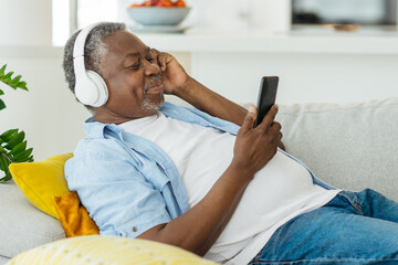 Handsome senior African man listening to the music and relaxing in his cozy apartment. - 456818082