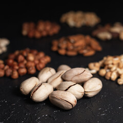 Pile of pecans in shell on black table with assorted blurred nuts in studio 