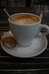 Cup of coffee with cookie on black background
