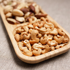 Closeup of pile of cashew nuts in wooden plate on table prepared for healthy snack 