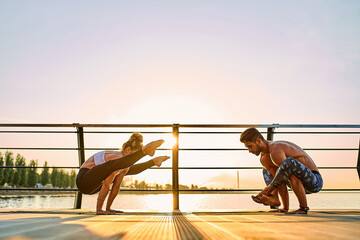Obraz premium Couple practicing acrobatic yoga together on nature outdoors at sea.